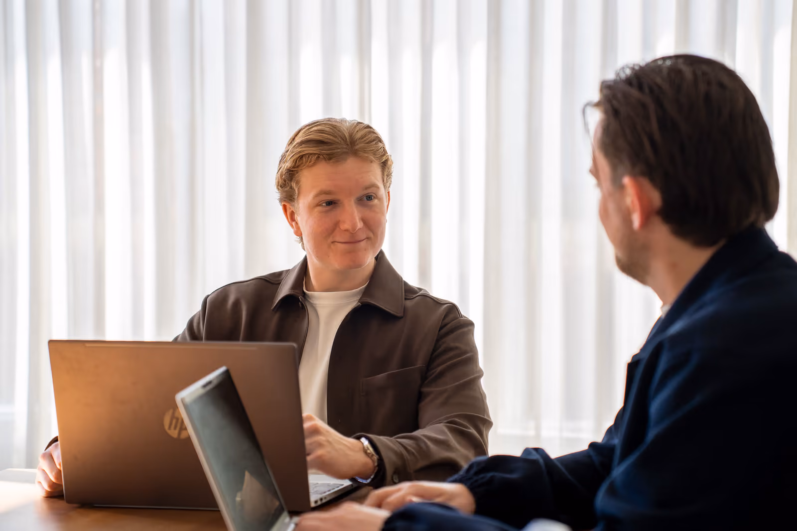 Timo in gesprek aan tafel met de laptop open